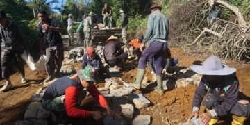 Kompak, Satgas TMMD dan Warga Turunkan Batu Dari Kendaraan Pickup