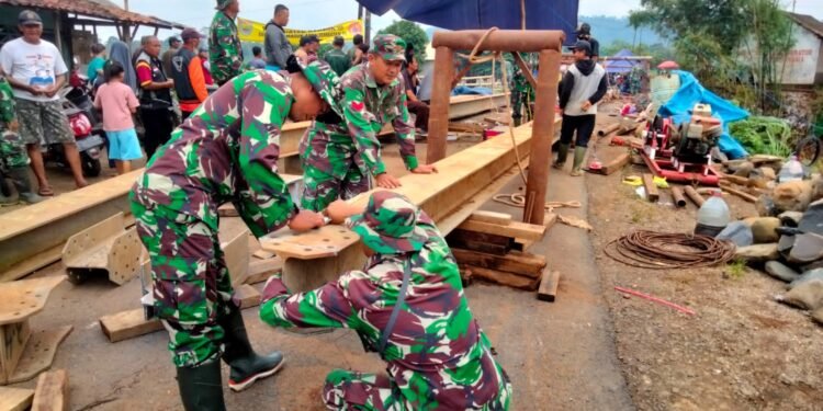 Babinsa Koramil 06/Tersono Bantu Perbaiki Jembatan Kalibelo Yang Rusak Akibat Banjir Bandang