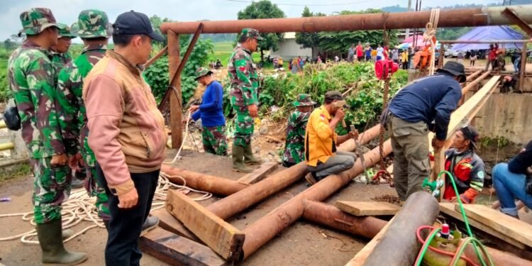 Babinsa Koramil 06/Tersono Bantu Perbaiki Jembatan Kalibelo Yang Rusak Akibat Banjir Bandang