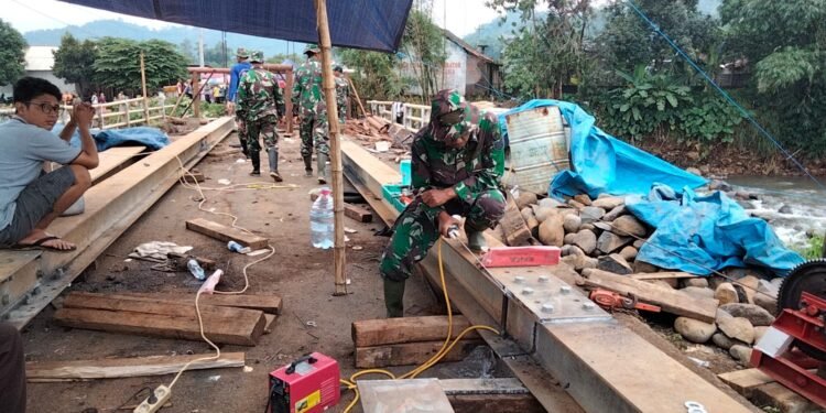 Babinsa Koramil 06/Tersono Bantu Perbaiki Jembatan Kalibelo Yang Rusak Akibat Banjir Bandang