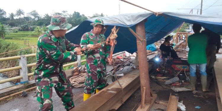 Babinsa Koramil 06/Tersono Bantu Perbaiki Jembatan Kalibelo Yang Rusak Akibat Banjir Bandang