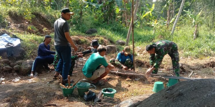 Warga bersama TNI melakukan perakitan besi untuk pondasi cakar ayam sebagai bagian dari pembangunan infrastruktur jembatan