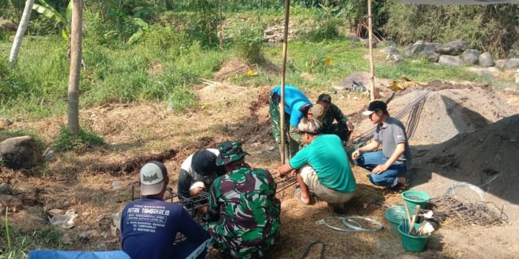 Warga bersama TNI melakukan perakitan besi untuk pondasi cakar ayam sebagai bagian dari pembangunan infrastruktur jembatan
