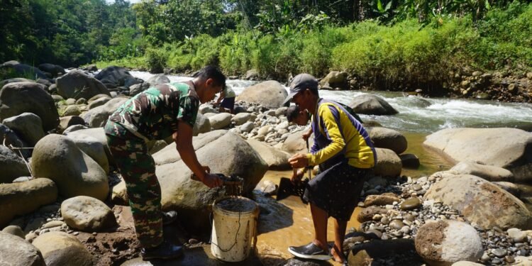 Babinsa 07/Bandar Bersama Warga Pecahkan Batu Sungai Matrial cor tanggul Jembatan Garuda