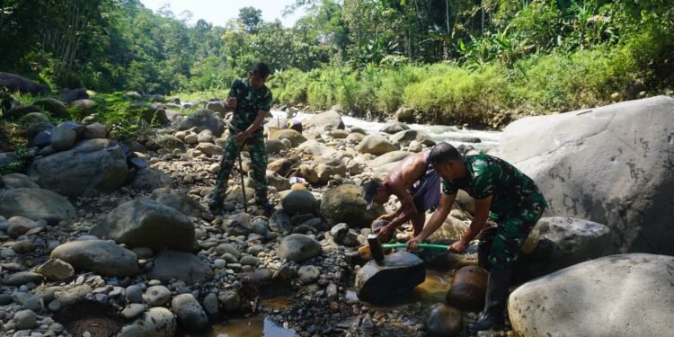 Babinsa 07/Bandar Bersama Warga Pecahkan Batu Sungai Matrial cor tanggul Jembatan Garuda